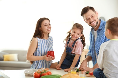 Photo of Happy family with children having breakfast in kitchen
