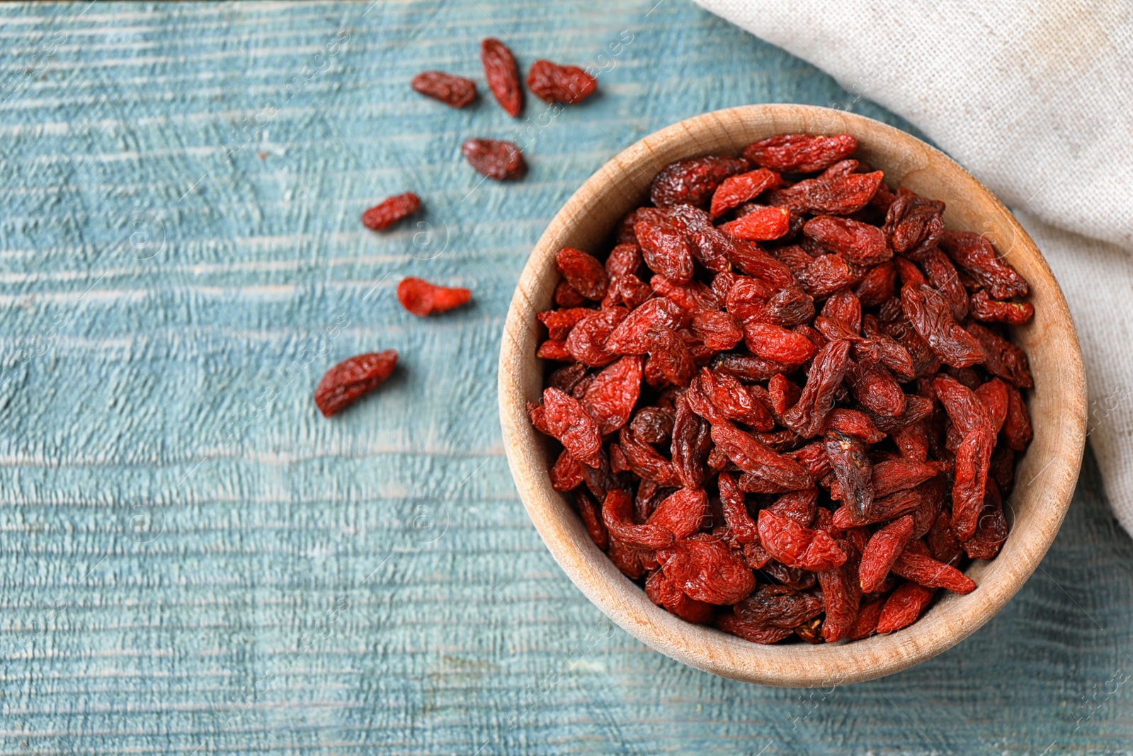 Photo of Dried goji berries on blue wooden table, flat lay