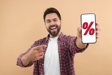 Discount, offer, sale. Man pointing at mobile phone with percent sign on screen, beige background