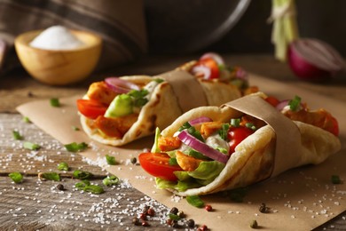 Photo of Delicious pita wraps with meat and vegetables on wooden table, closeup
