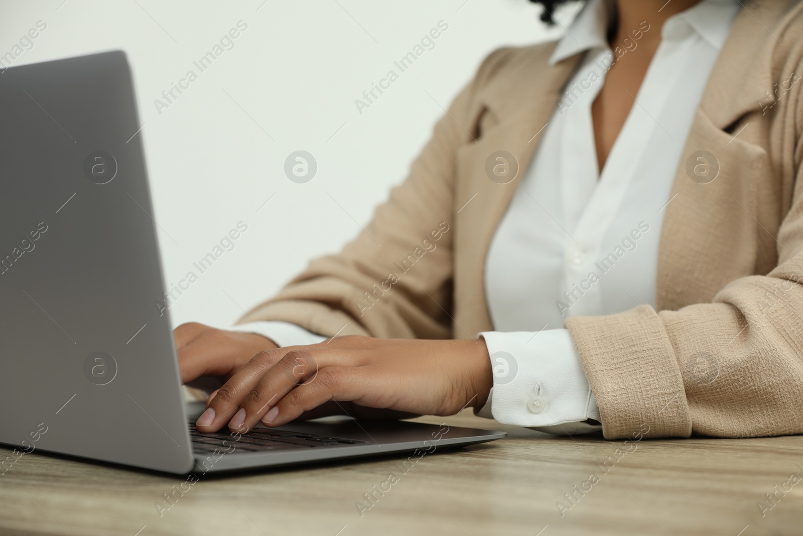 Photo of Woman using laptop at wooden desk indoors, closeup