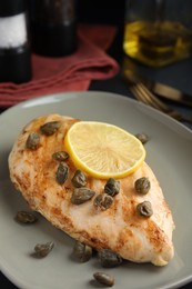 Photo of Delicious chicken fillet with capers and lemon on plate, closeup