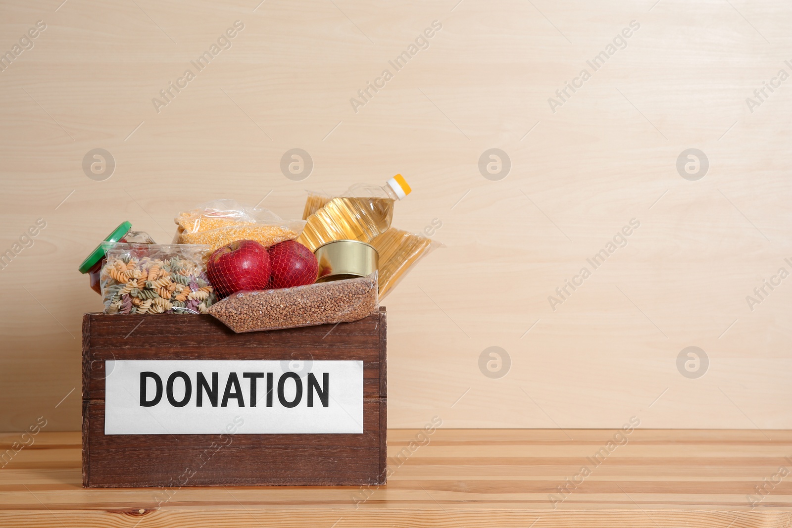 Photo of Donation box with food on table against light background. Space for text