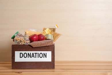 Photo of Donation box with food on table against light background. Space for text