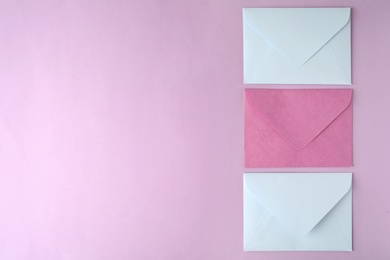 Photo of Colorful paper envelopes on pink background, flat lay. Space for text