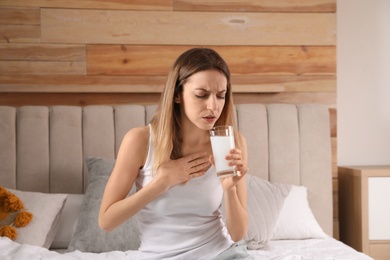 Photo of Woman taking medicine for hangover on bed at home