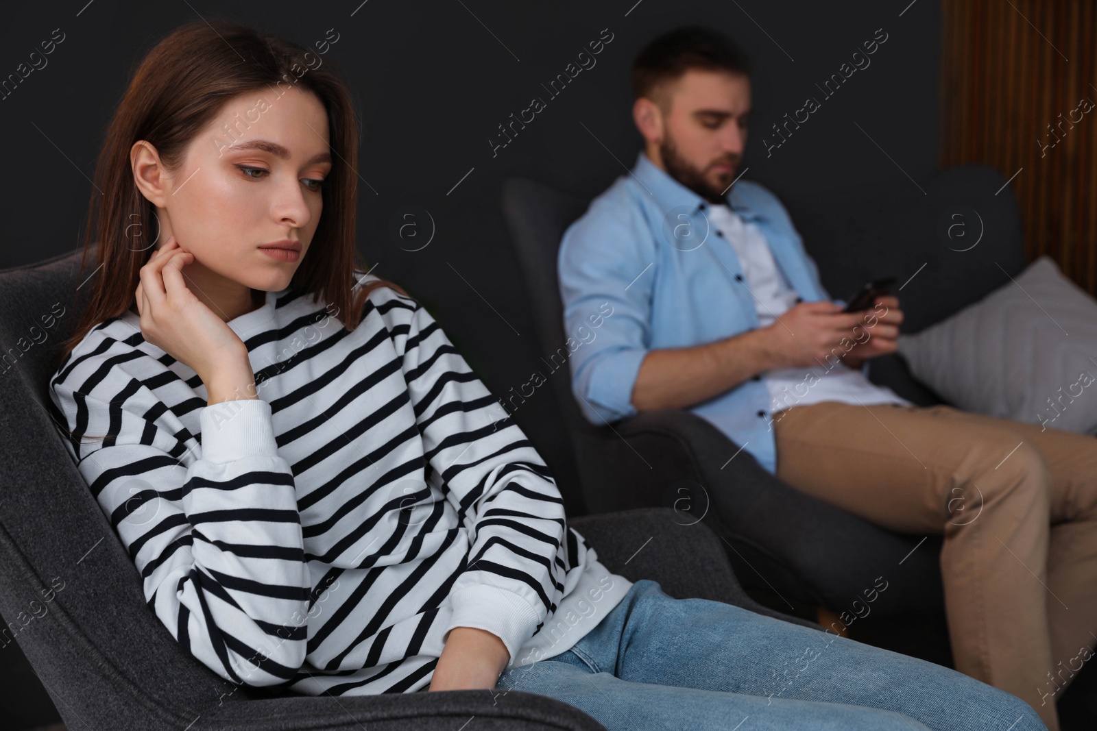 Photo of Man preferring smartphone over his girlfriend at home, focus on woman. Relationship problems