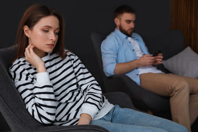 Photo of Man preferring smartphone over his girlfriend at home, focus on woman. Relationship problems