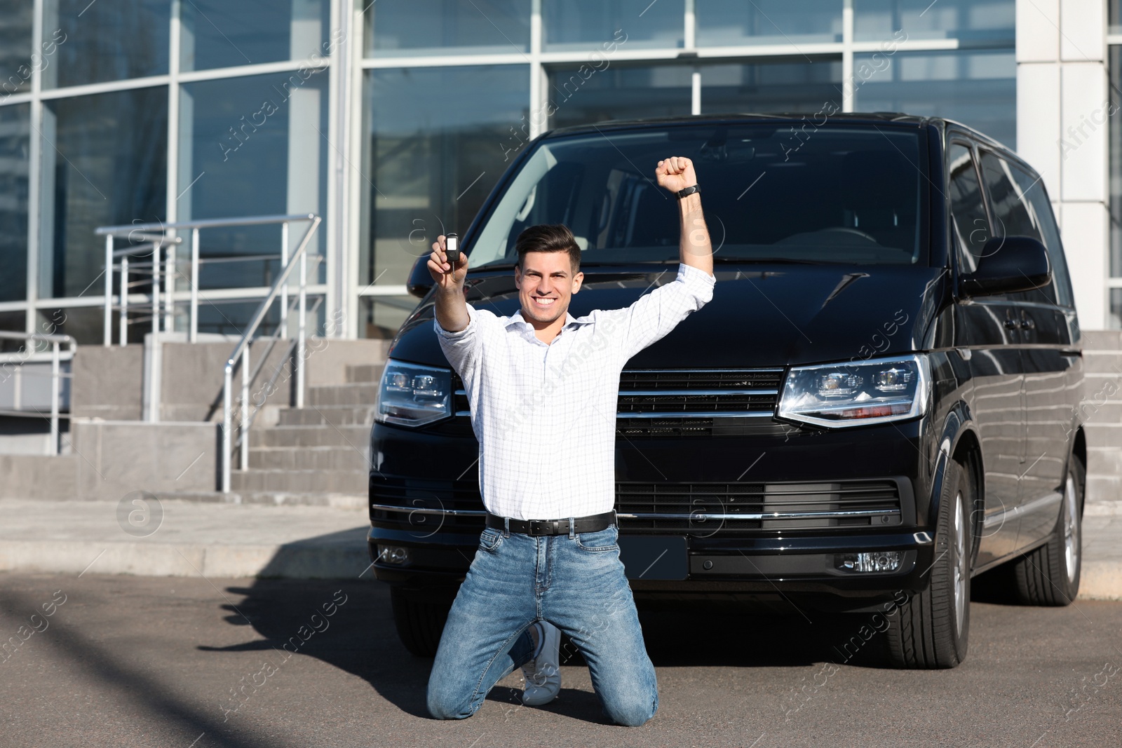 Photo of Excited man with key near car on city street. Buying new auto