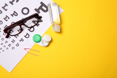 Photo of Flat lay composition with eye chart, glasses and contact lens accessories on color background