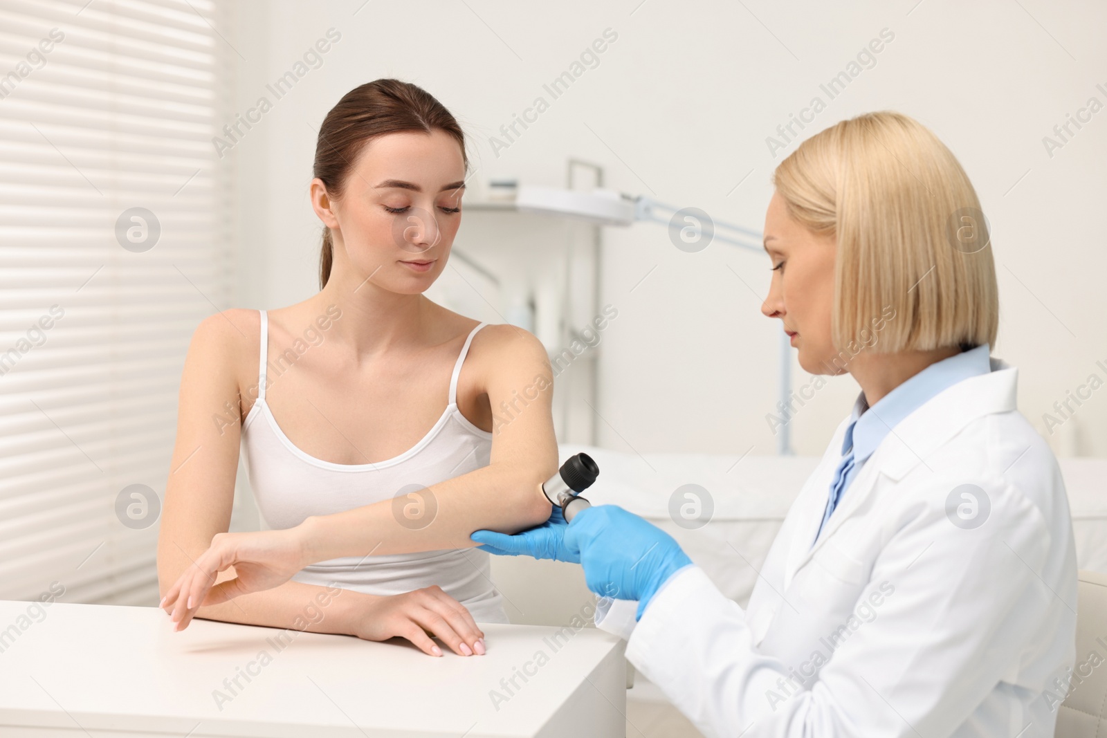 Photo of Dermatologist with dermatoscope examining patient in clinic