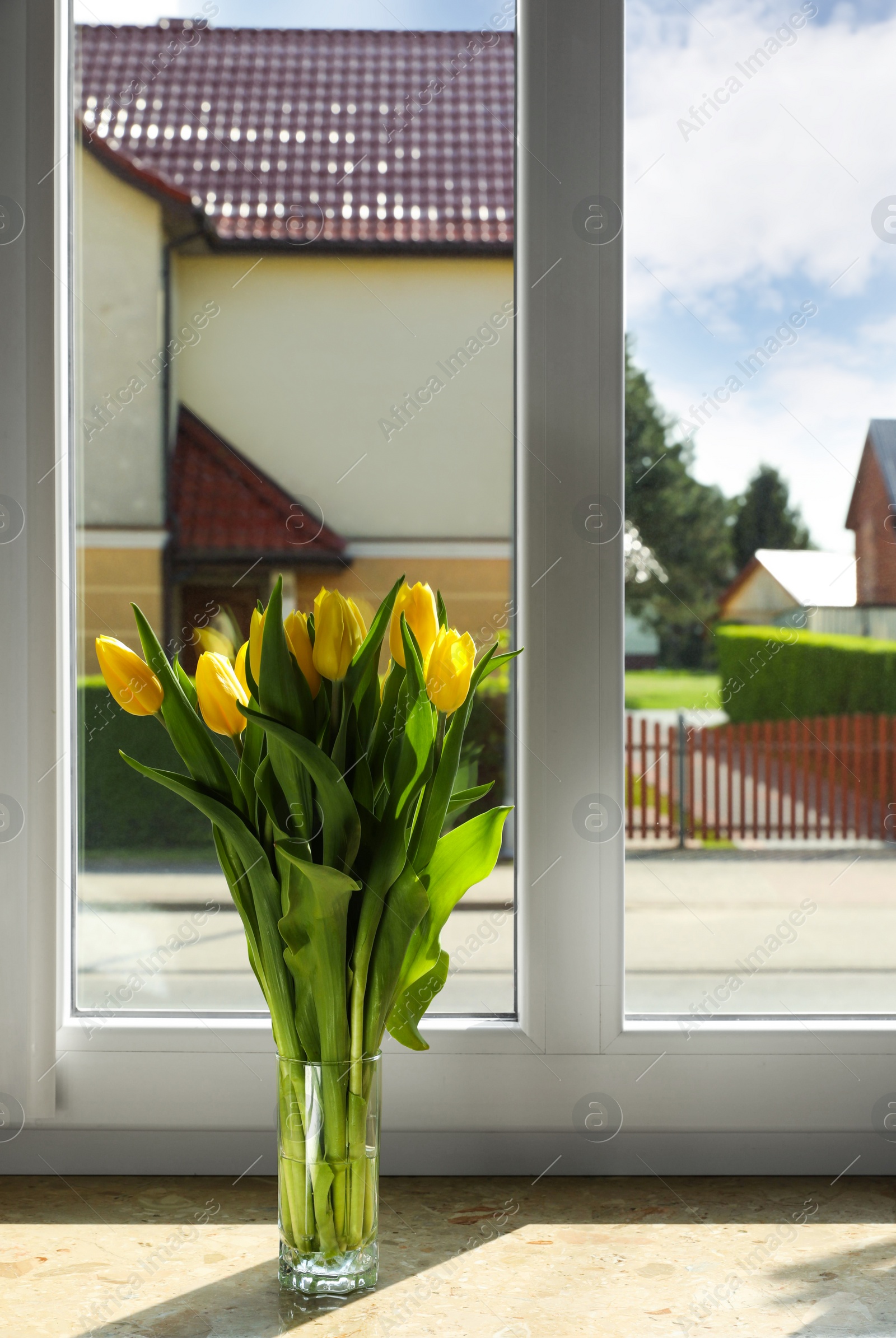Photo of Bouquet of beautiful yellow tulip flowers in glass vase on windowsill. Space for text