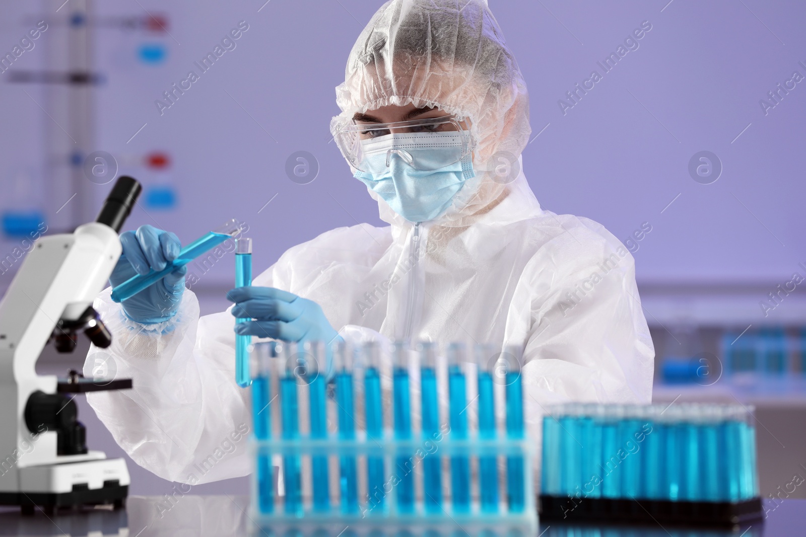 Photo of Scientist working with test tubes of light blue liquid in laboratory
