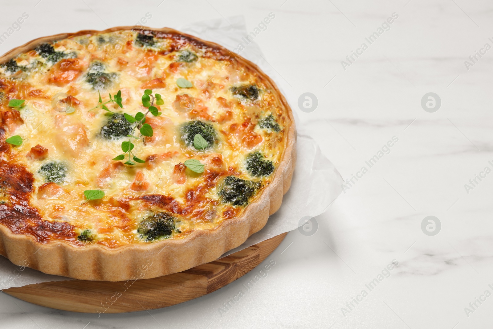 Photo of Delicious homemade quiche with salmon and broccoli on white table, space for text