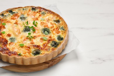 Delicious homemade quiche with salmon and broccoli on white table, space for text