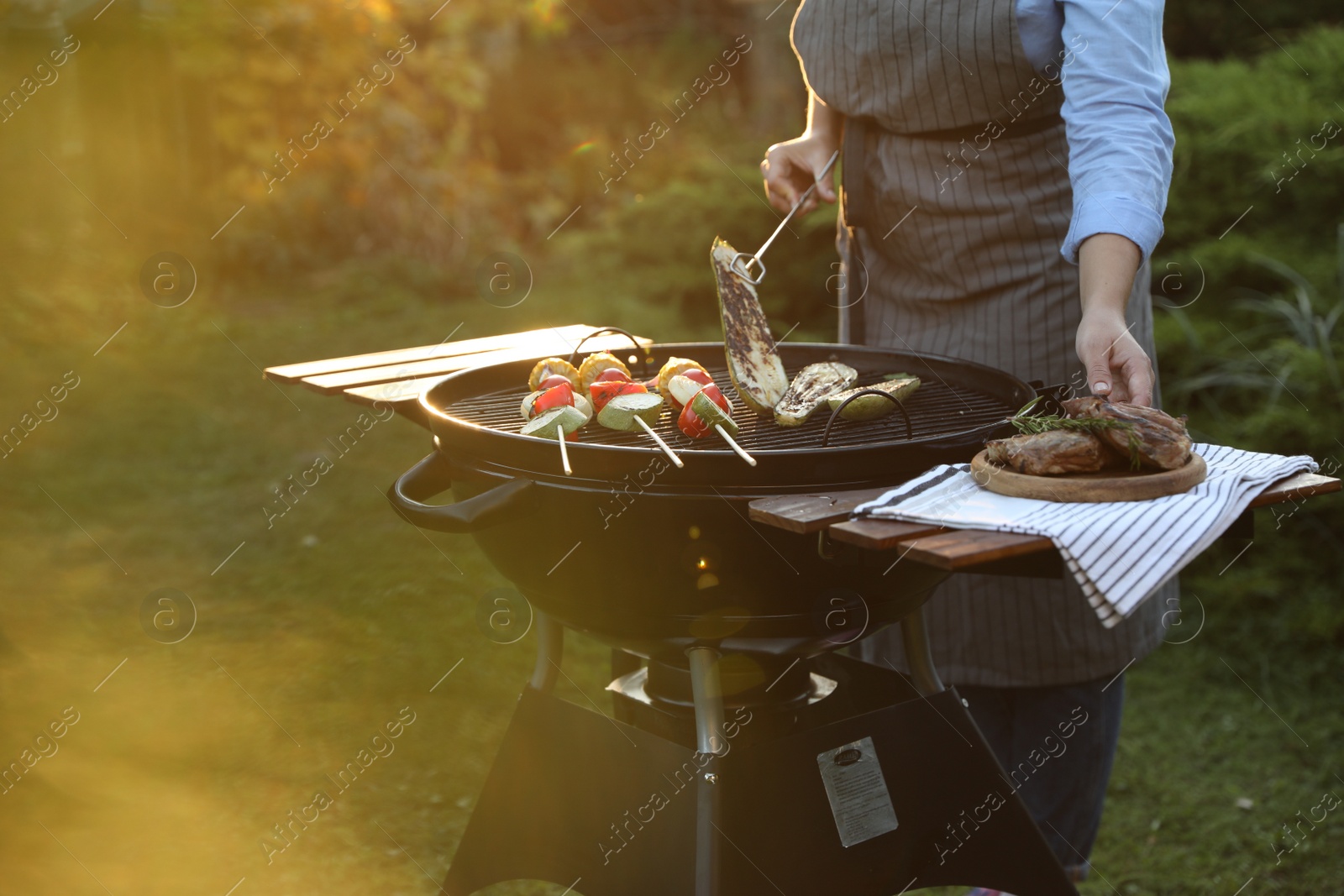 Photo of Woman cooking vegetables on barbecue grill outdoors, closeup