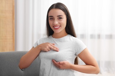 Photo of Beautiful young woman doing breast self-examination at home