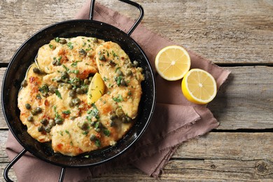 Photo of Delicious chicken piccata with herbs and lemon on wooden table, flat lay