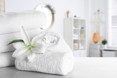 Image of Fresh towels and lily flower on light grey marble table in bathroom. Space for text