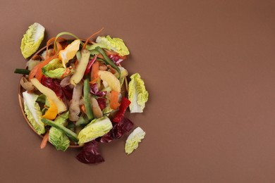 Photo of Peels of fresh vegetables on brown background, top view. Space for text