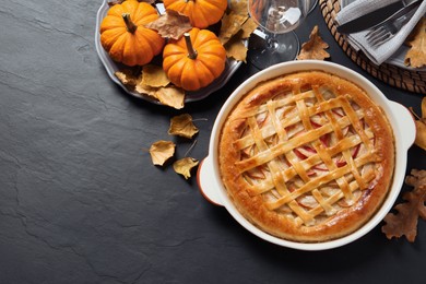 Photo of Delicious homemade apple pie and autumn decor on black table, flat lay. Space for text