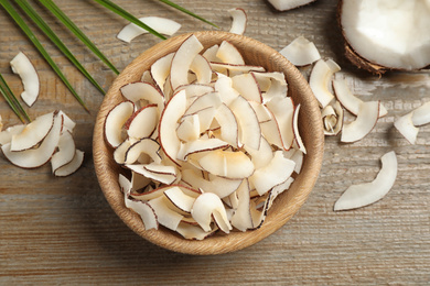 Photo of Tasty coconut chips on wooden table, flat lay