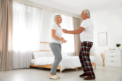 Happy mature couple dancing together in bedroom
