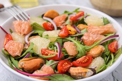 Delicious pomelo salad with tomatoes and mussels on table, closeup view