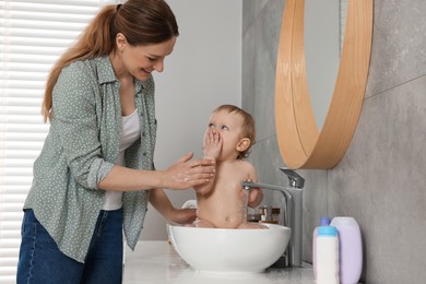 Photo of Mother washing her little baby in sink at home