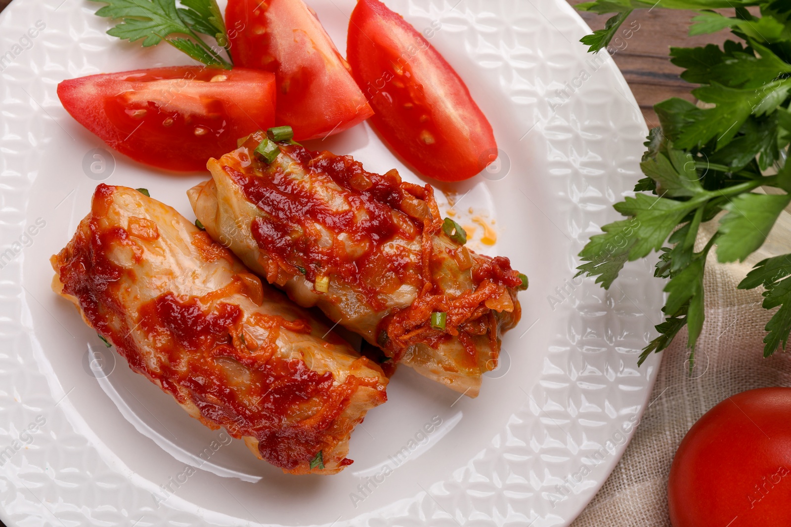 Photo of Delicious stuffed cabbage rolls with tomatoes on table, flat lay