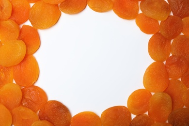 Photo of Frame made of dried apricots on white background, top view with space for text. Healthy fruit