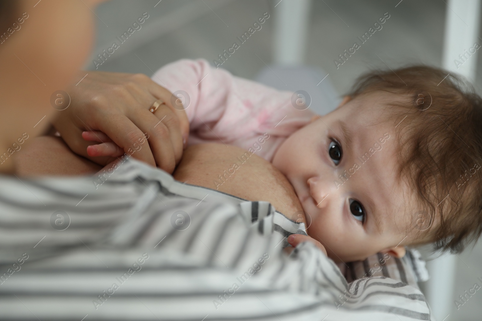 Photo of Young woman breastfeeding her baby at home, closeup