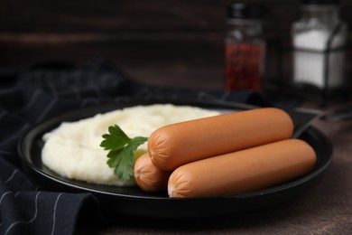 Photo of Delicious boiled sausages, mashed potato and parsley on brown table, closeup