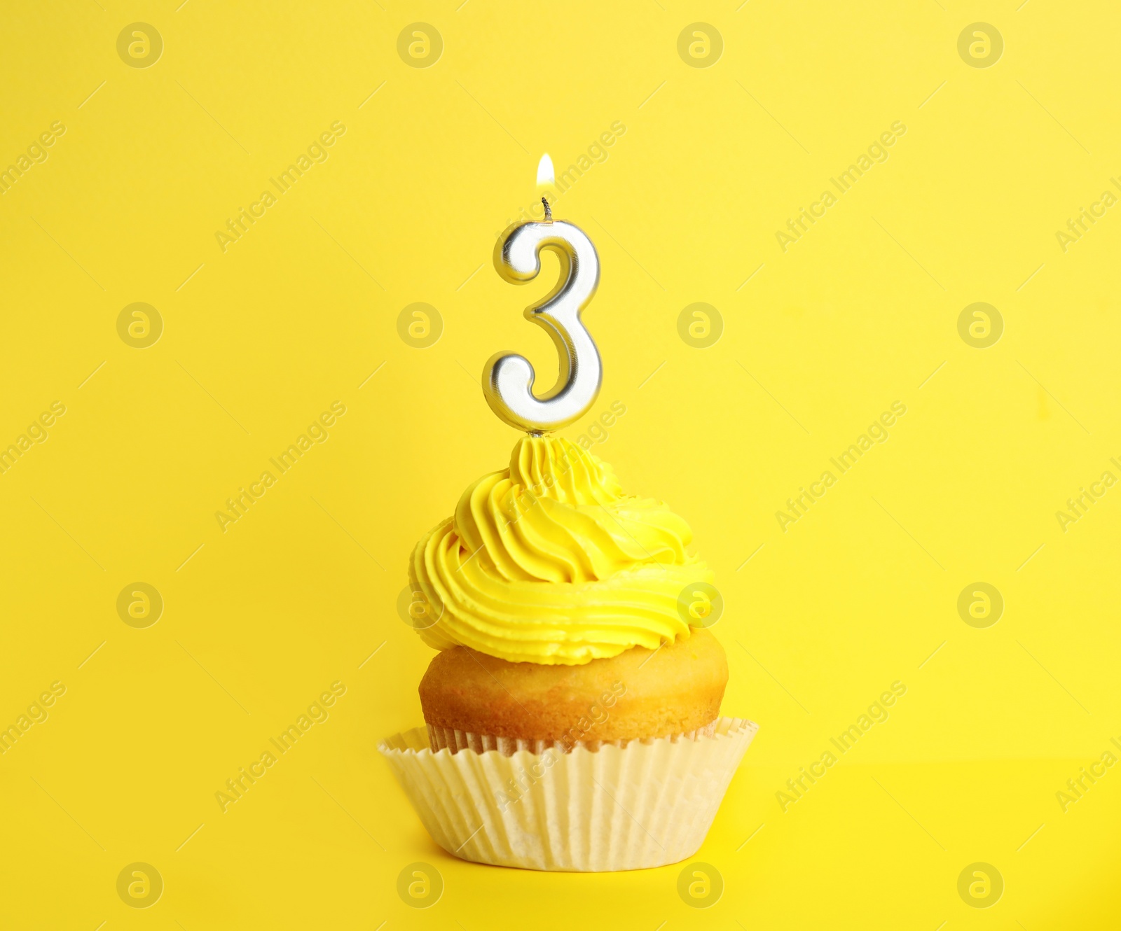 Photo of Birthday cupcake with number three candle on yellow background