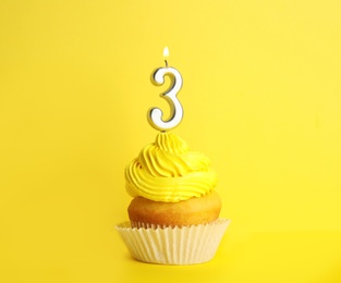 Birthday cupcake with number three candle on yellow background