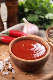 Photo of Delicious ketchup in bowl and spices on table, closeup. Tomato sauce