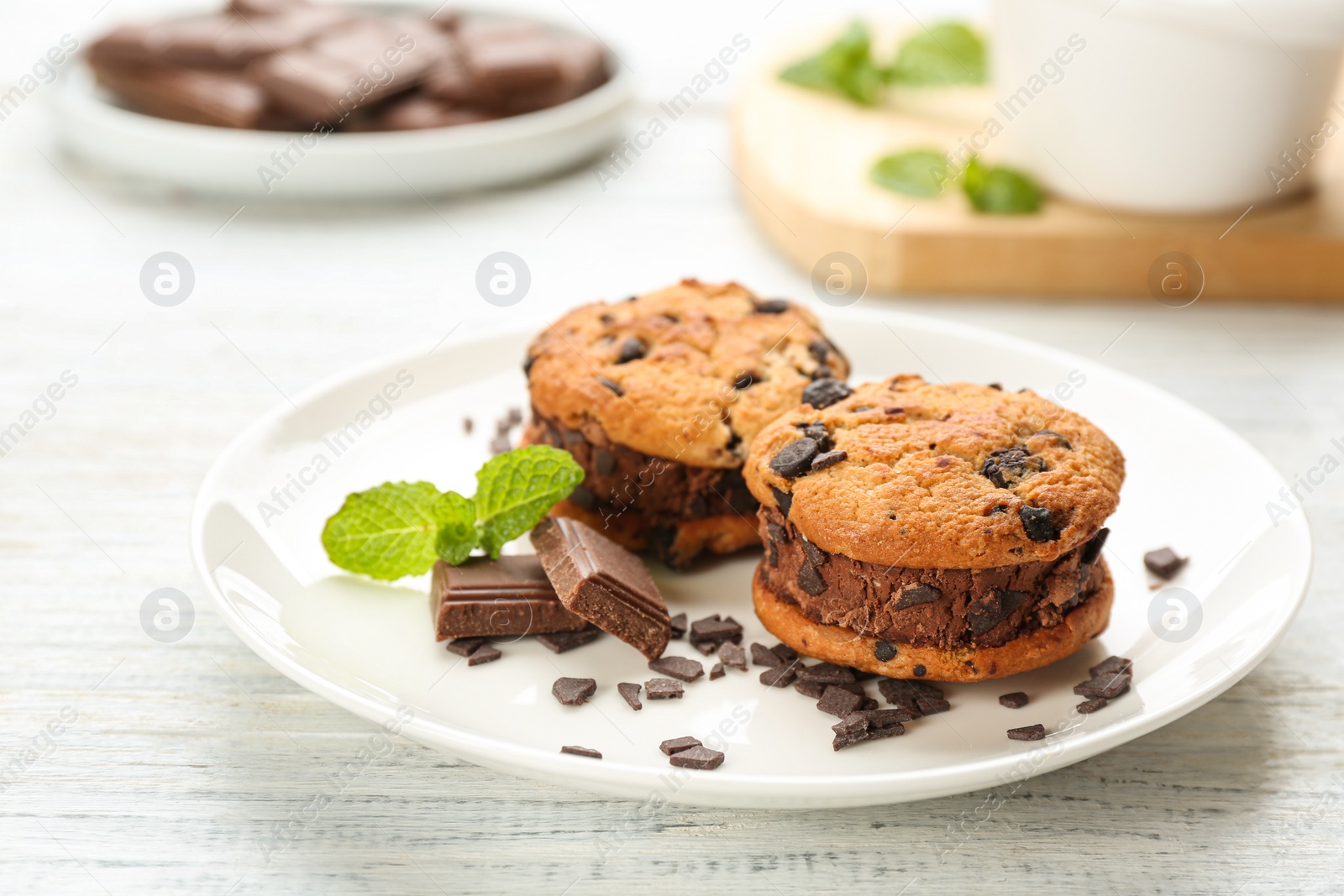 Photo of Sweet delicious ice cream cookie sandwiches and chocolate on white wooden table