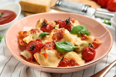 Tasty ravioli with tomato sauce served on table, closeup