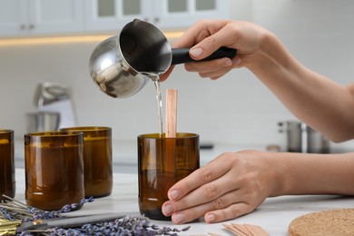 Photo of Woman making homemade candle at table in kitchen, closeup