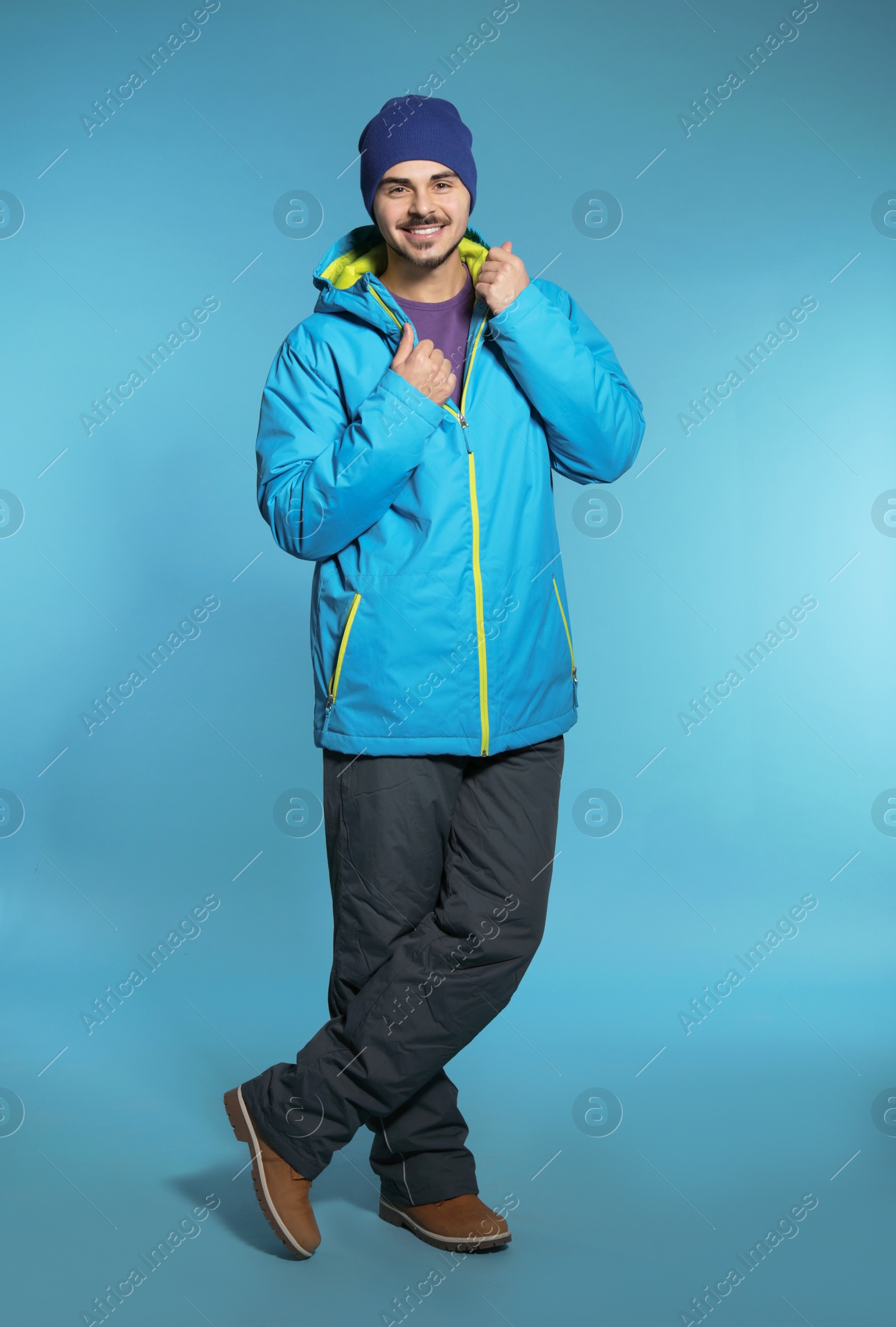 Photo of Young man wearing warm clothes on color background. Ready for winter vacation