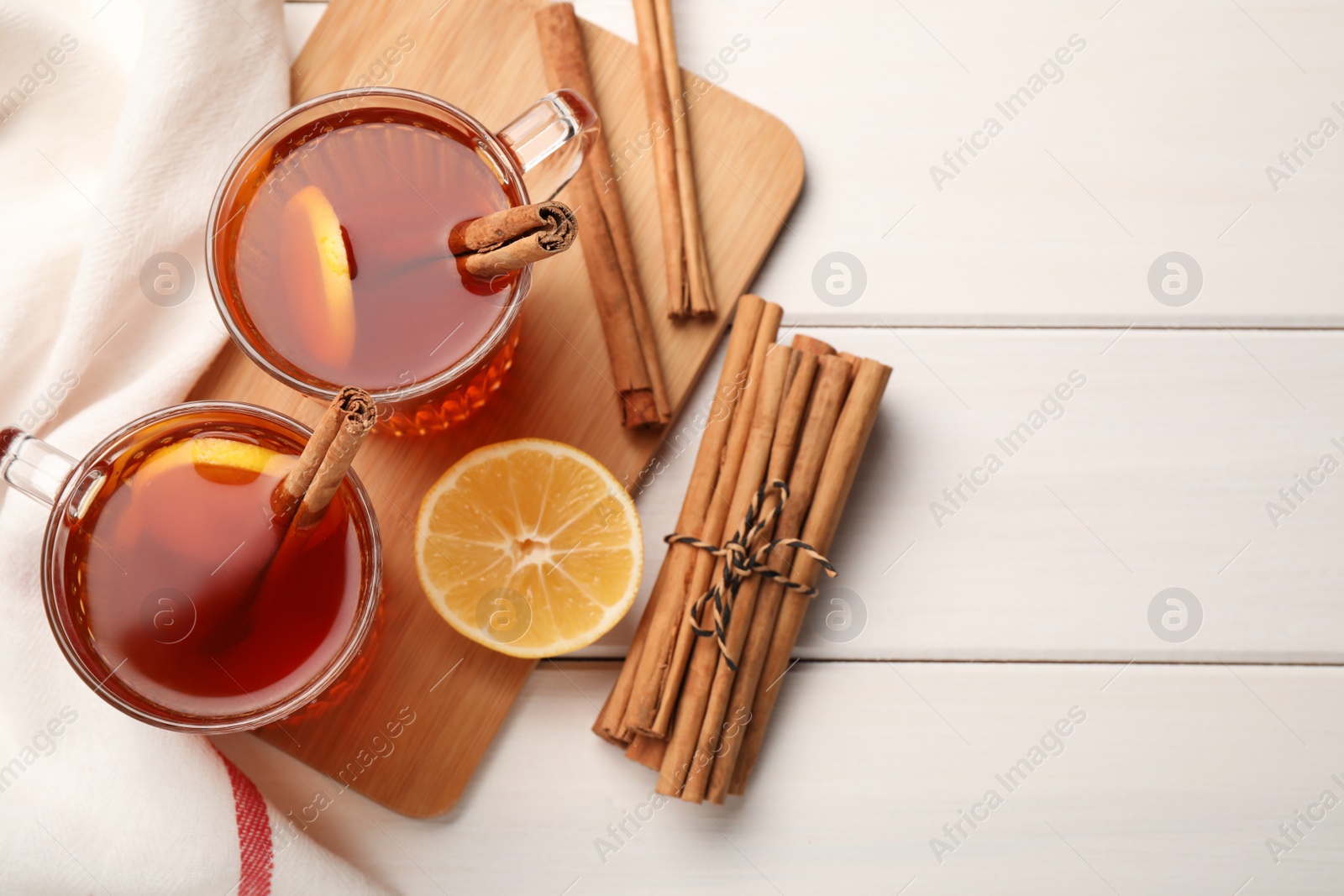 Photo of Delicious hot tea with cinnamon and lemon on white wooden table, flat lay. Space for text