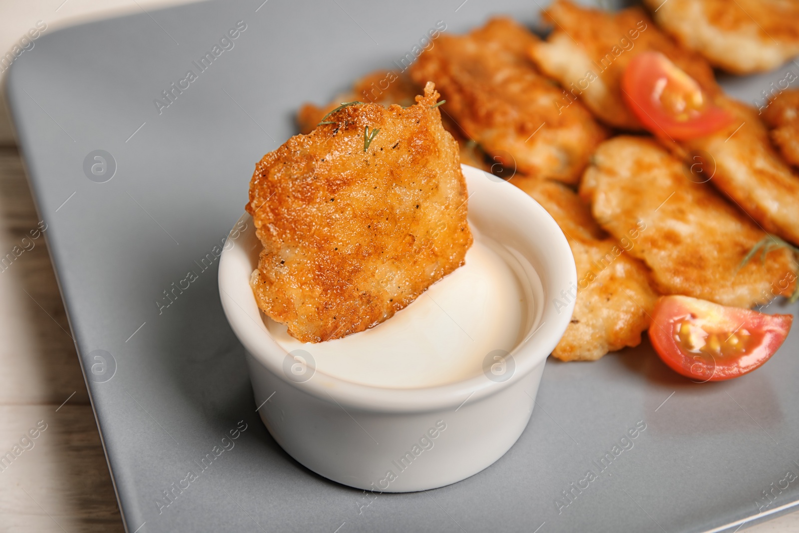 Photo of Plate with tasty potato fritters and sauce, closeup