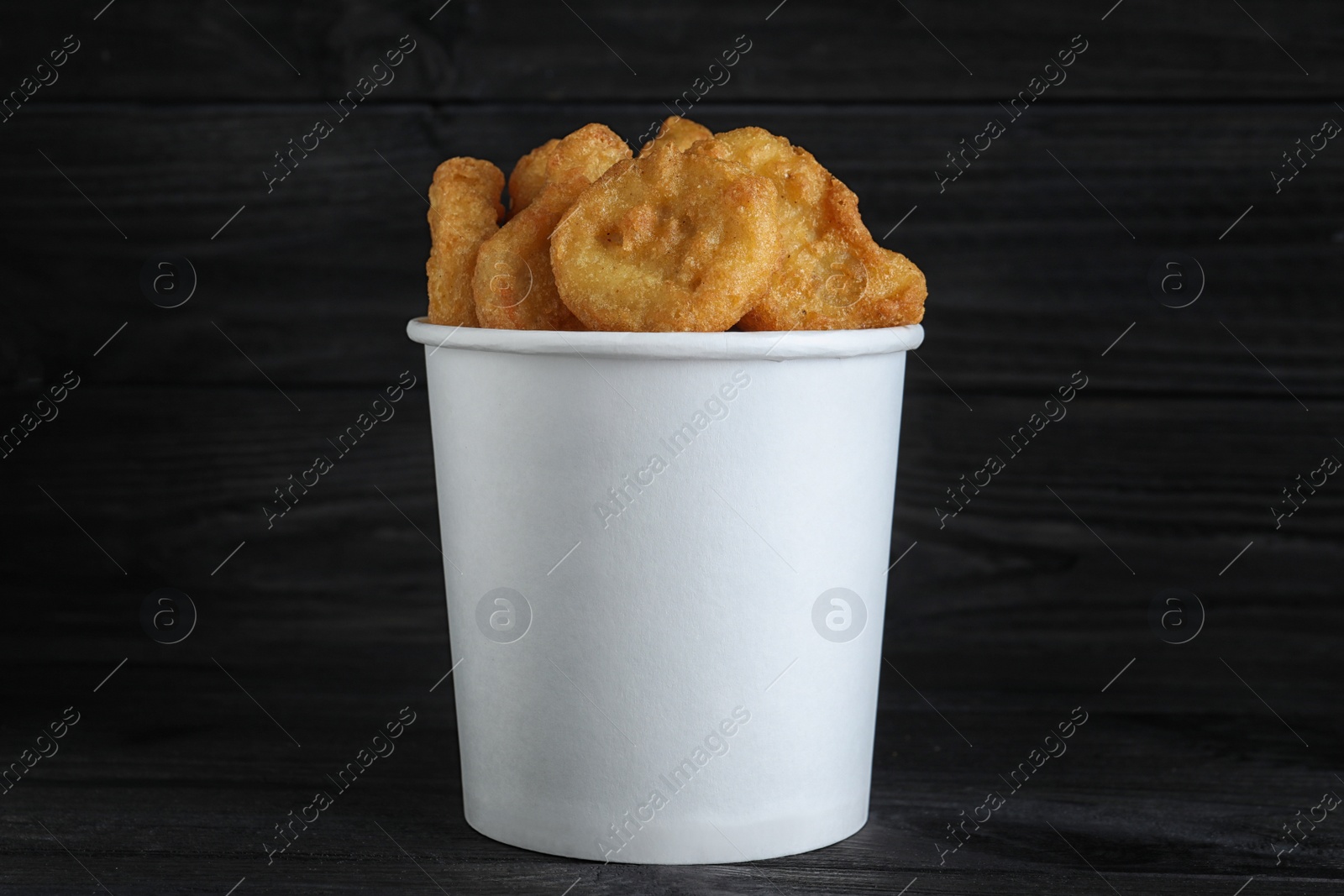 Photo of Bucket with tasty chicken nuggets on black table