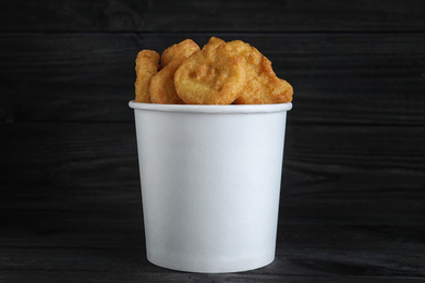 Photo of Bucket with tasty chicken nuggets on black table
