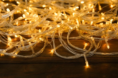 Beautiful glowing Christmas lights on wooden background