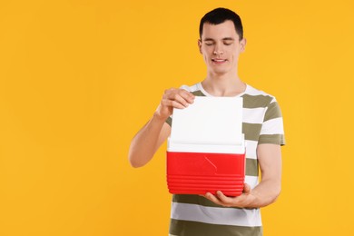 Photo of Man with red cool box on orange background, space for text