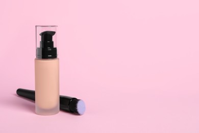 Bottle of skin foundation and brush on pink background, space for text. Makeup product