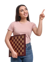 Photo of Happy woman with chessboard pointing upwards on white background