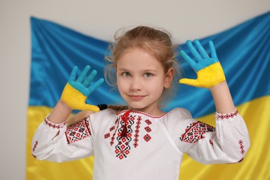 Photo of Little girl with painted hands near Ukrainian flag. Love Ukraine concept