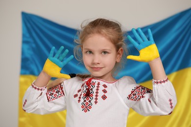 Little girl with painted hands near Ukrainian flag. Love Ukraine concept